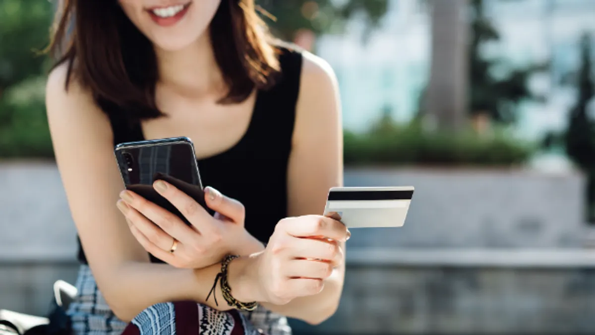 Woman looking at her credit card and phone