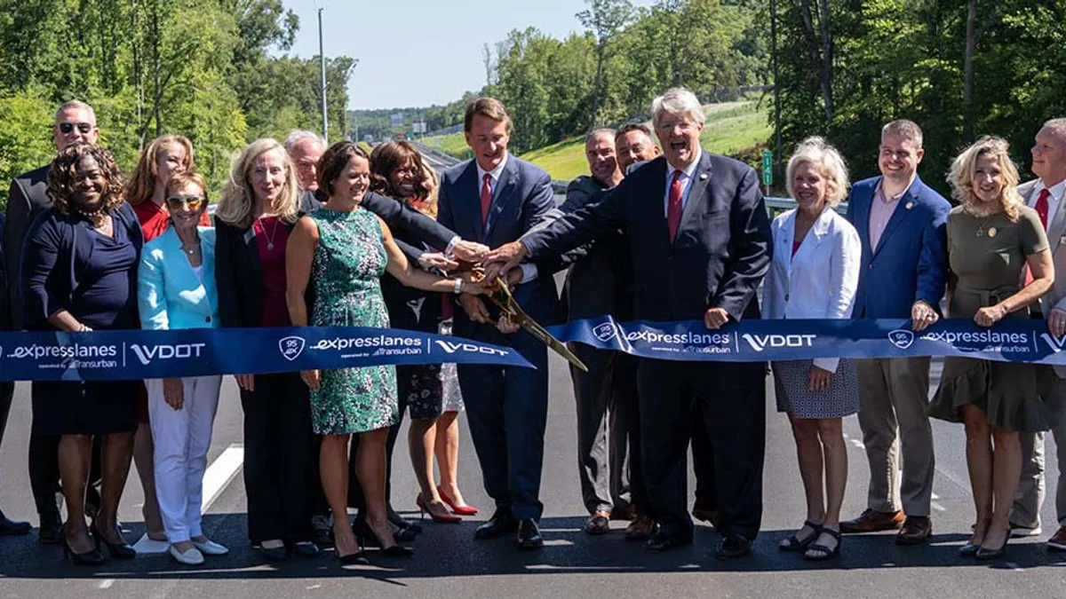 Group of people stand behind a long blue ribbon.