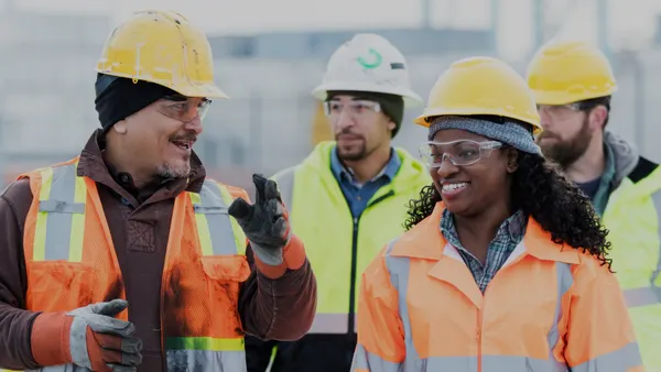 A group of people in safety gear walking and talking on a construction jobsite.