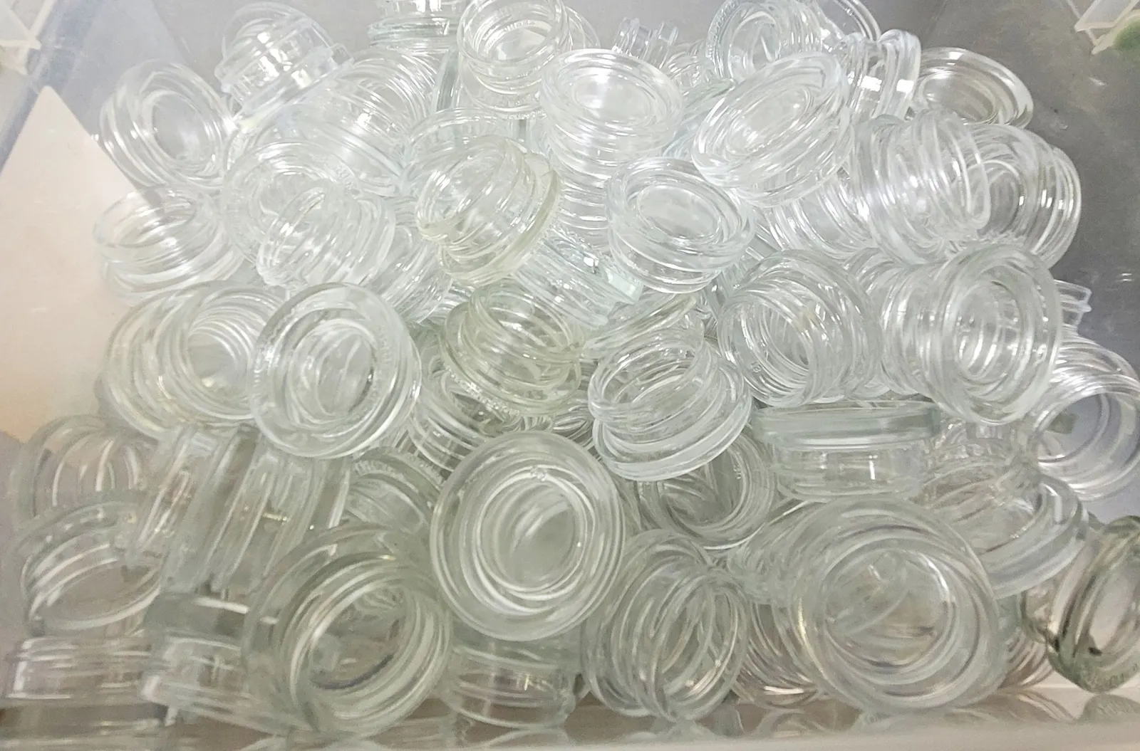 A close-up view of dozens of small, clear glass jars.