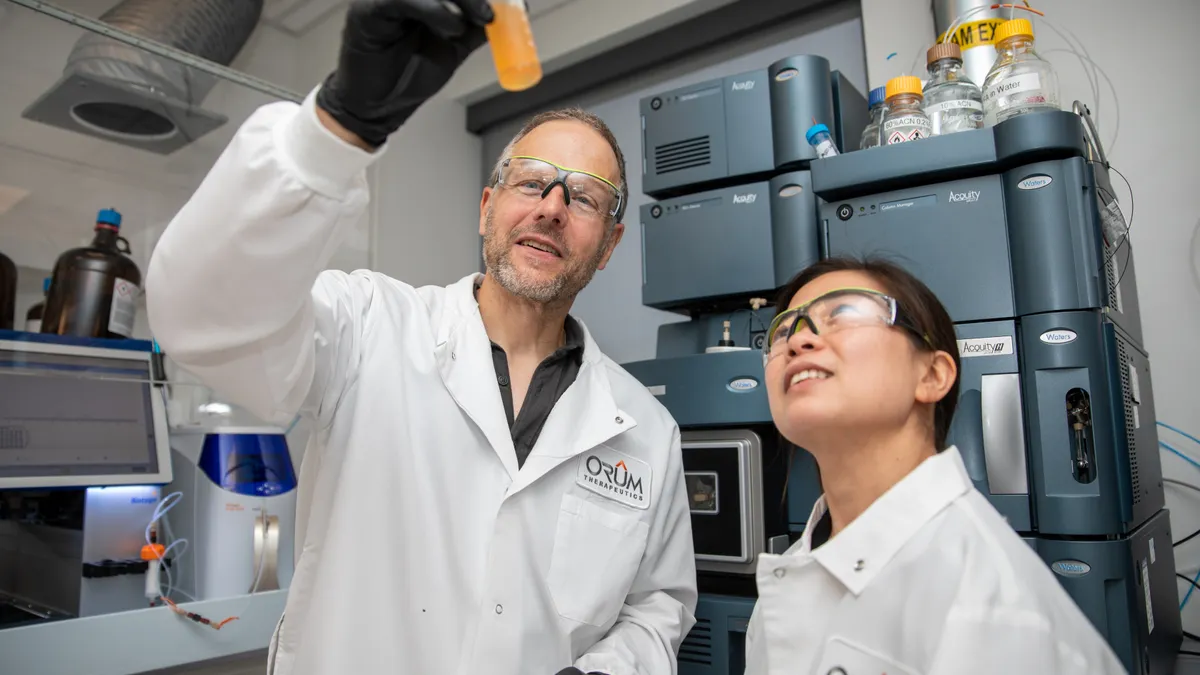 Scientists at Orum Therapeutics observing the physical appearance of an experiment.