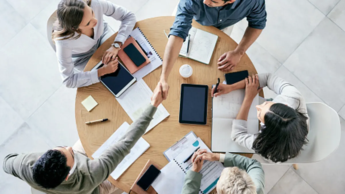 Shot of people shaking hands during a team meeting in a modern office