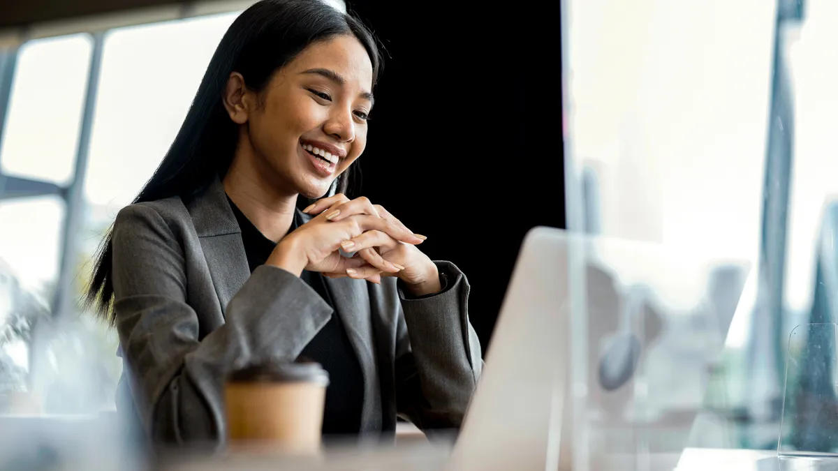 Young woman having video call on her laptop with client or business team to discuss on a business project in a modern business office.