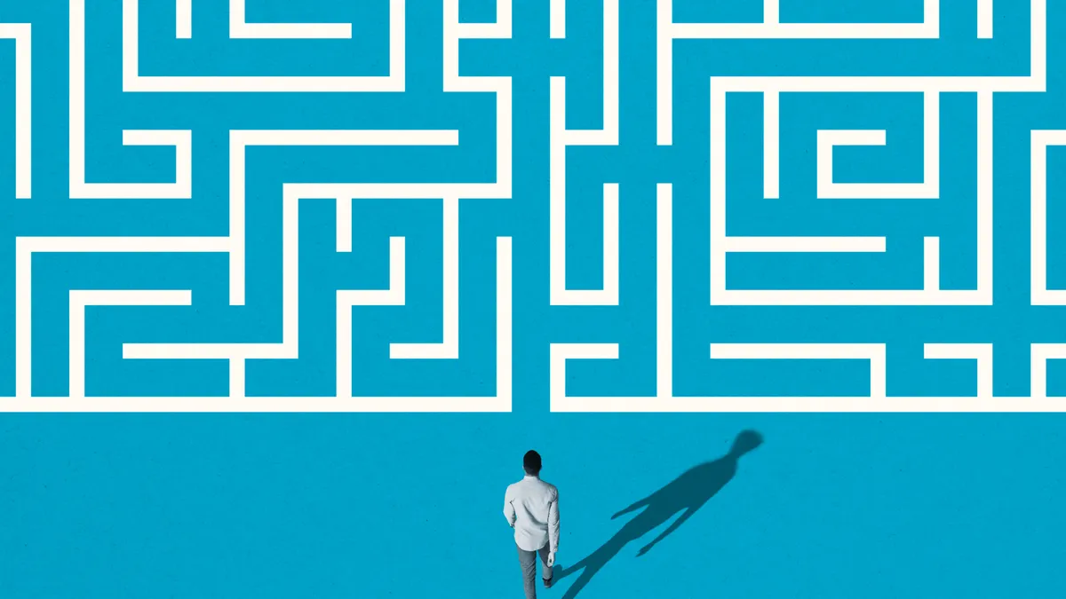 High angle rear view of young man walking towards white maze pattern over blue background