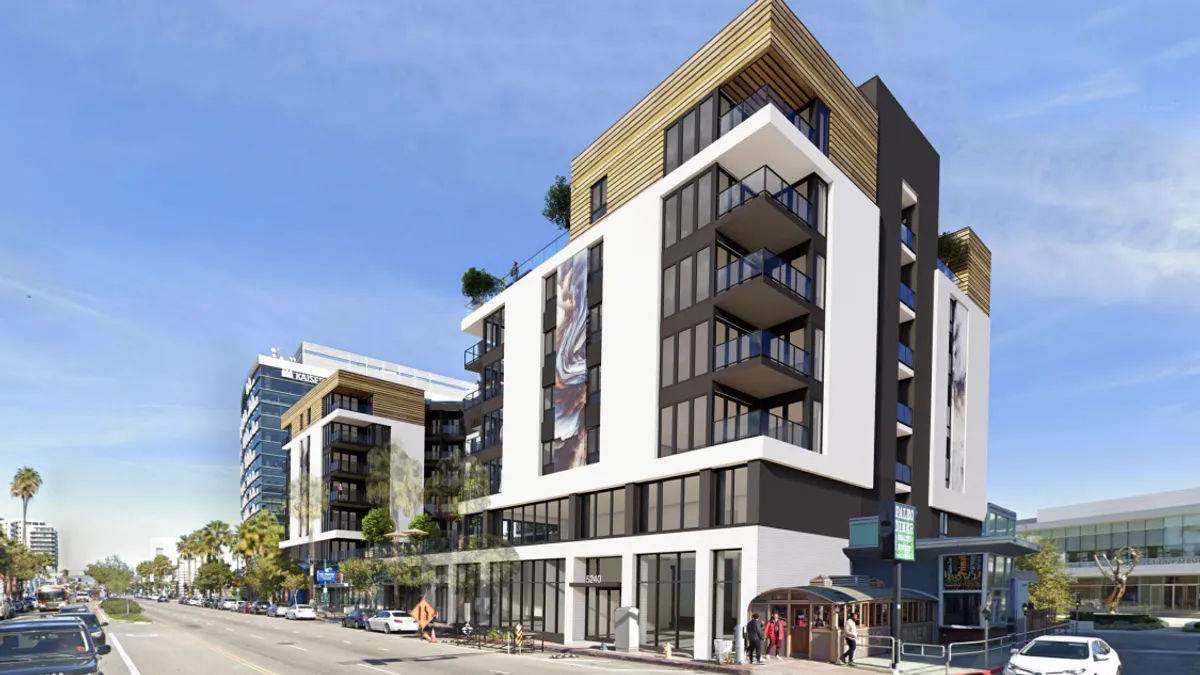 A mid-rise apartment building with a mural on the front, next to a street.