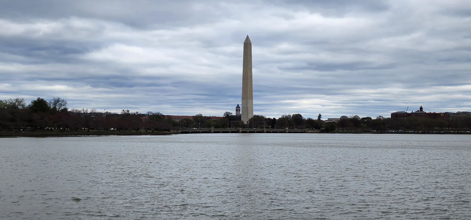 The Tidal Basin in Washington, D.C. with the monument in the background on a cloudy day.