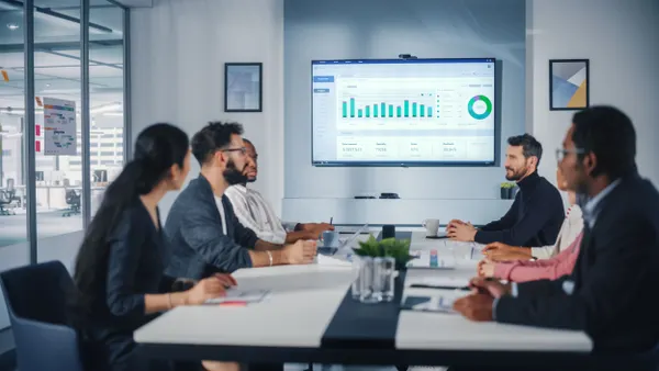 Team of business people discuss data analytics in a conference room.