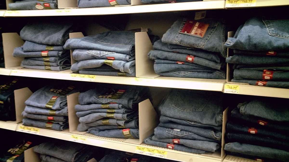 Folded pairs of jeans in various washes are folded and stacked neatly in a store display.