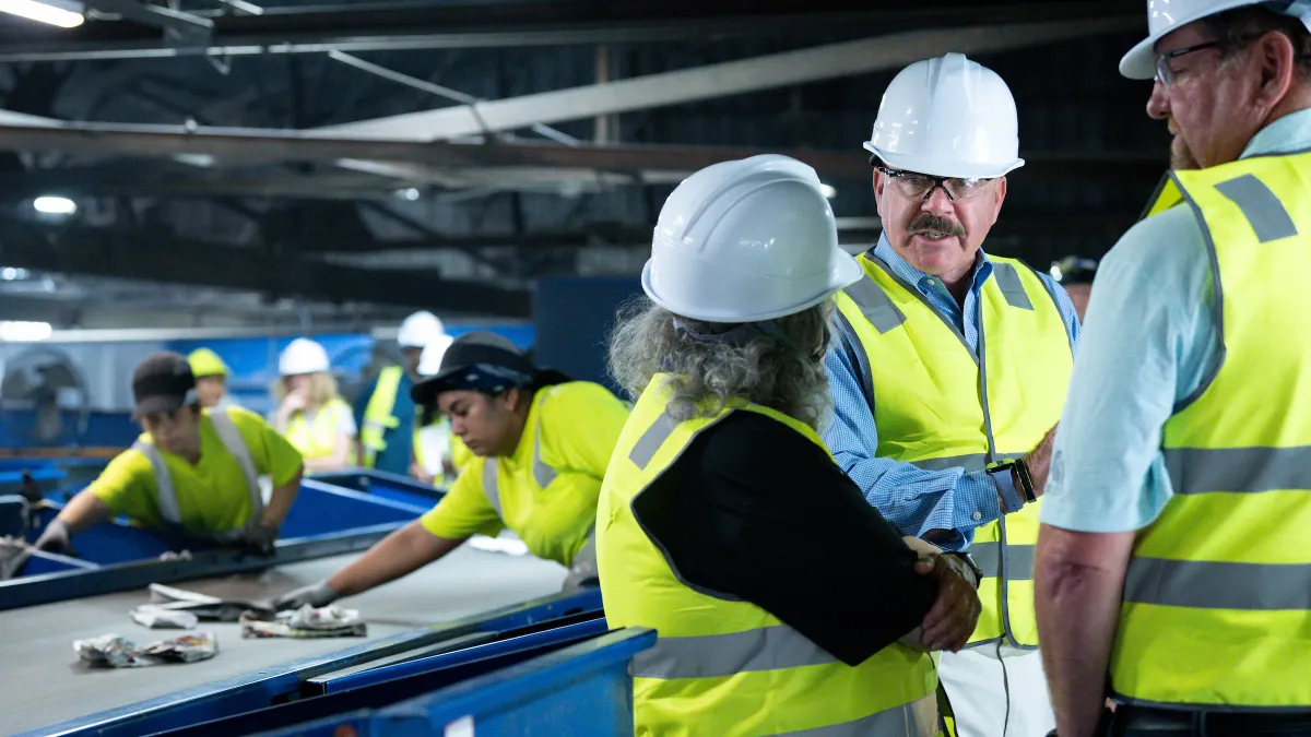 Workers talk in front of recycling equipment