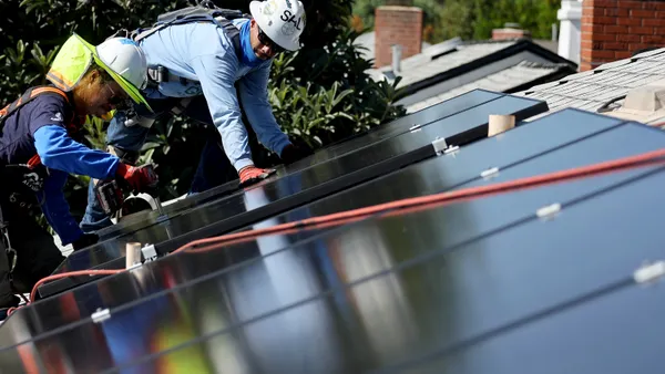 Two men install solar panels on a roof.