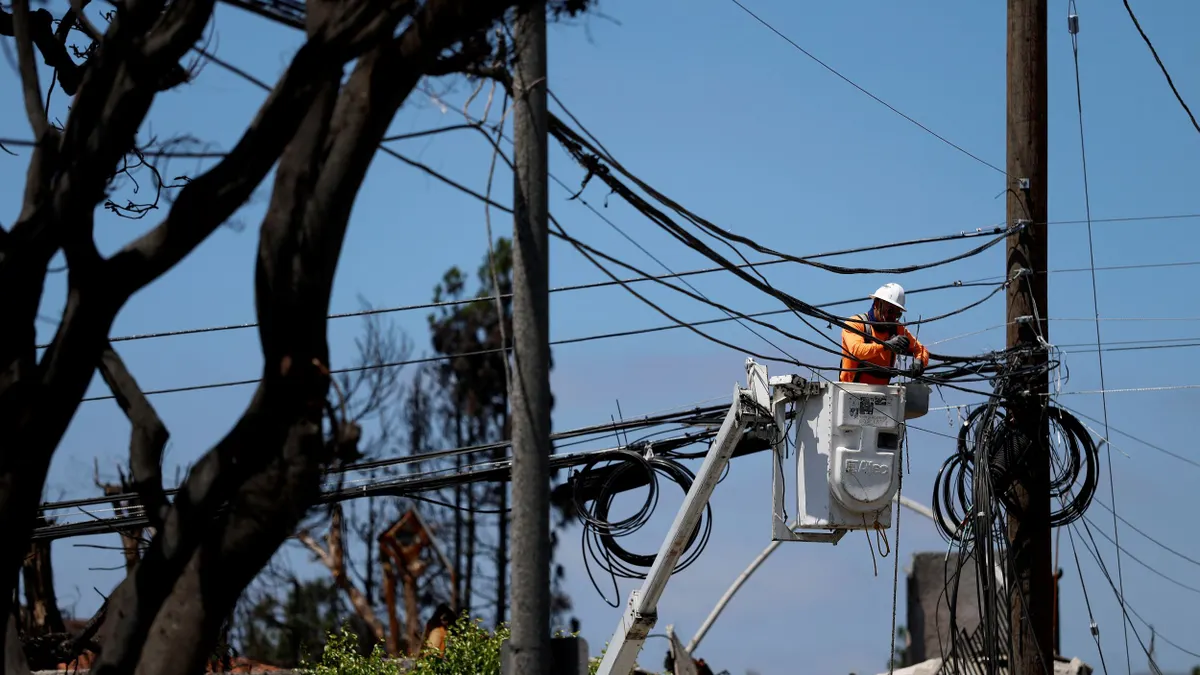 A utility worker repairs power lines