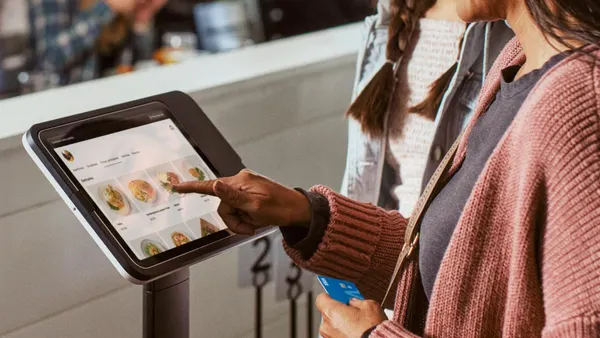 A person ordering food from a kiosk at a restaurant.