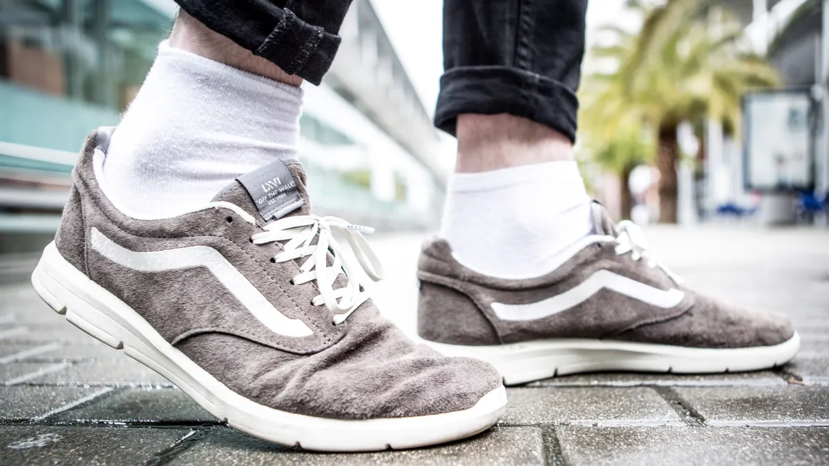 A closeup of a person's shoes, light grey Vans.
