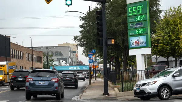 Cars at an intersection with a gas price sign on the corner.