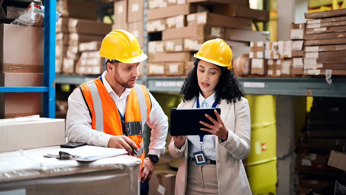 Two workers reviewing a tablet in a warehouse.