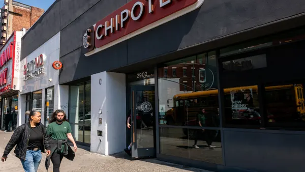 People walk past a Chipotle storefront.