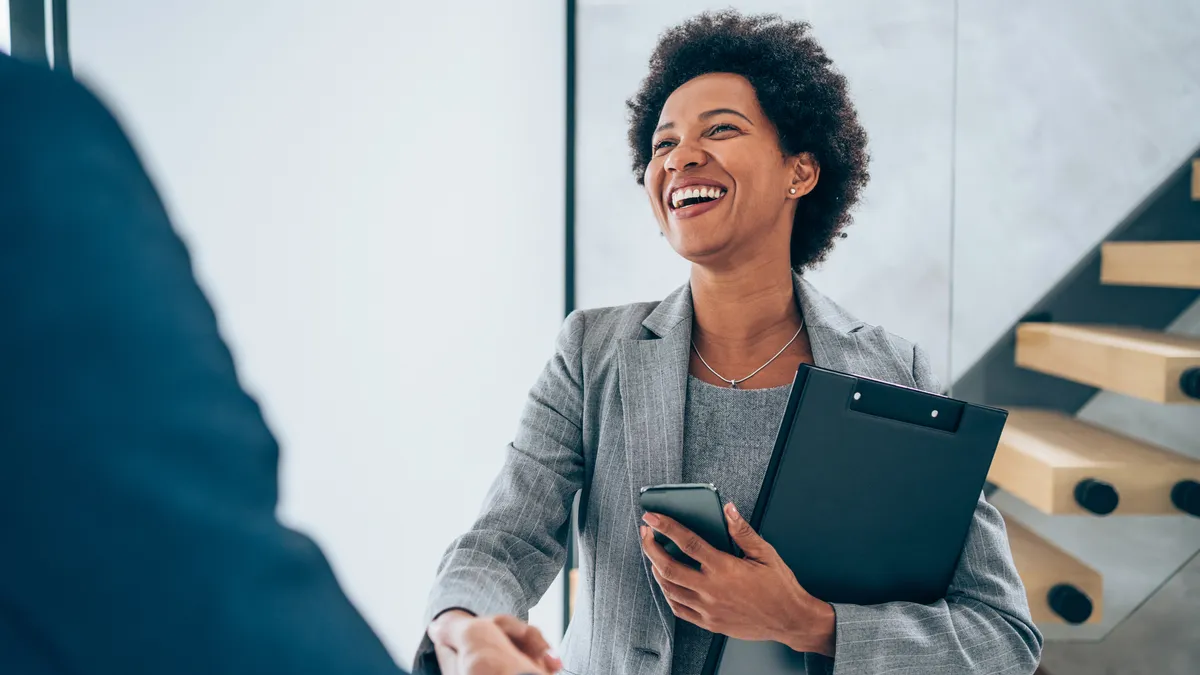 a smiling businessperson shakes a colleague's hand