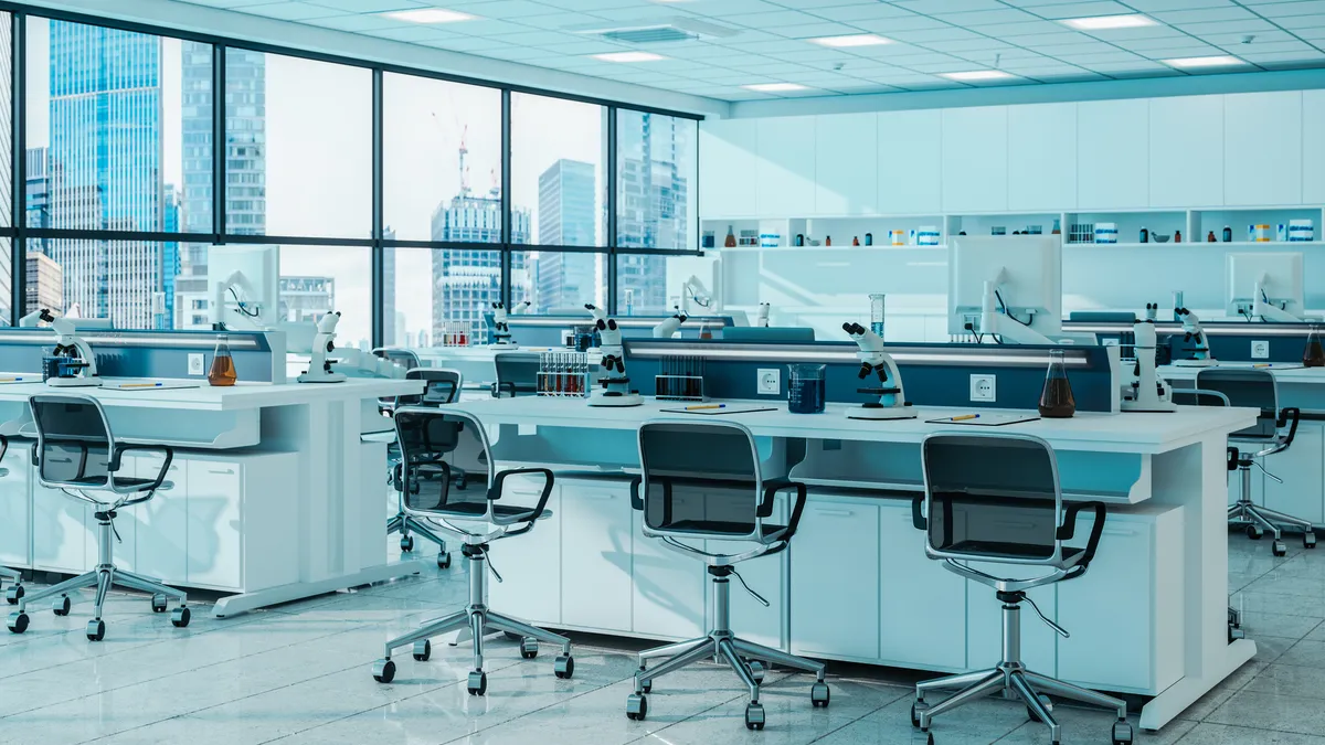 A view of a life sciences lab, with empty chairs and desks in front of a large city-facing window.