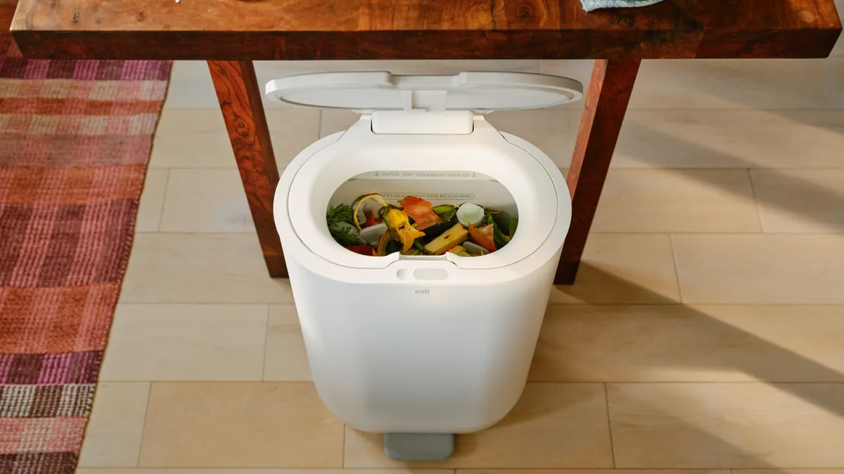 Overhead view of a sleek bin with a lid and food scraps piled inside.