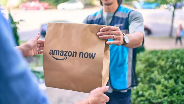 A person hands over a package labeled "Amazon Now."