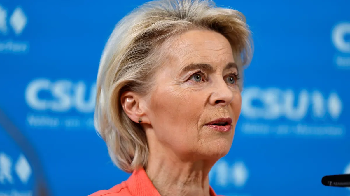 European Commission President Ursula von der Leyen speaks in front of a blue background.