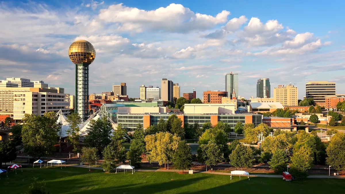 An evening shot of the Knoxville, Tennessee skyline. There is a water tower to the left, and a park in the foreground, with the rest of the city to the right.