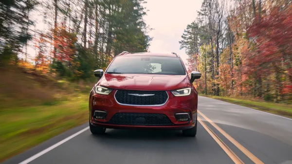 The front view of a red 2025 Chrysler Pacifica driving on a road.