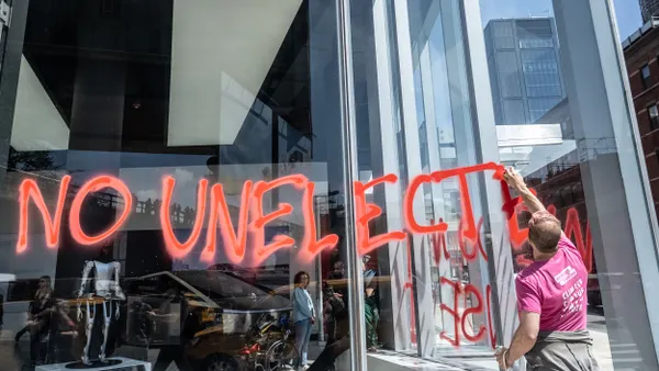 Protestors spray paint anti-DOGE messages outside an NYC Tesla showroom on Ap 22, 2025