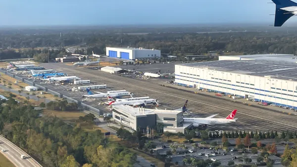 A row of planes lined up facing two factories.