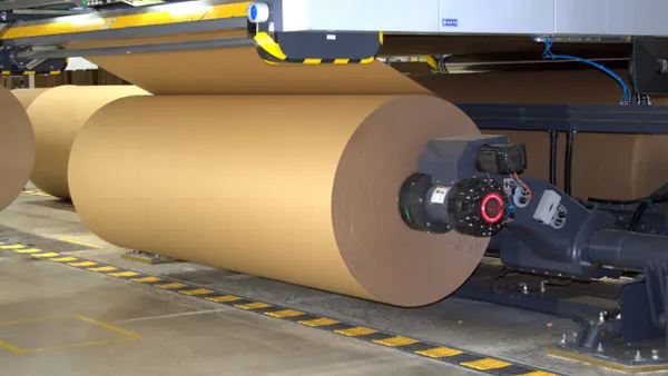 Large rolls of fiber material on industrial equipment inside a manufacturing facility.
