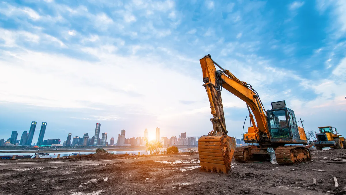 Excavator in construction site on sunset sky background