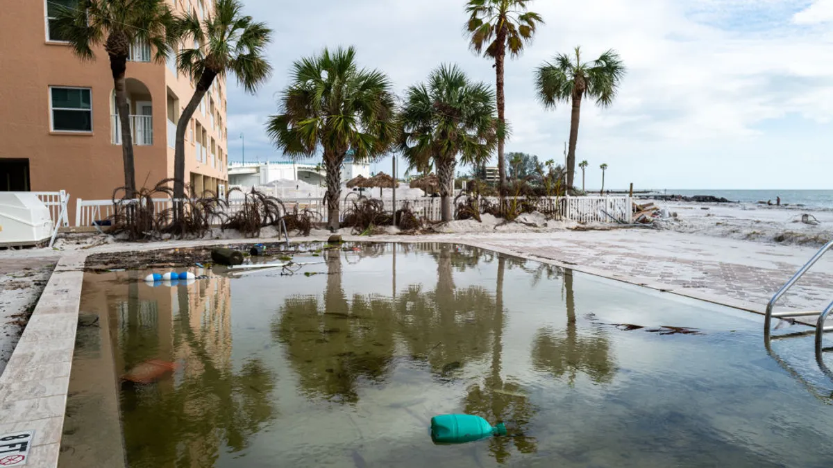 A hotel pool on the beach filled with debris.