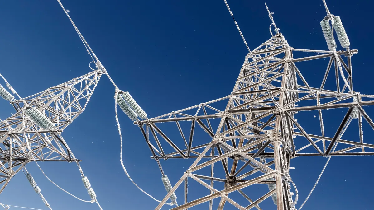 High-voltage wires and poles are covered with frost on a frosty winter day.