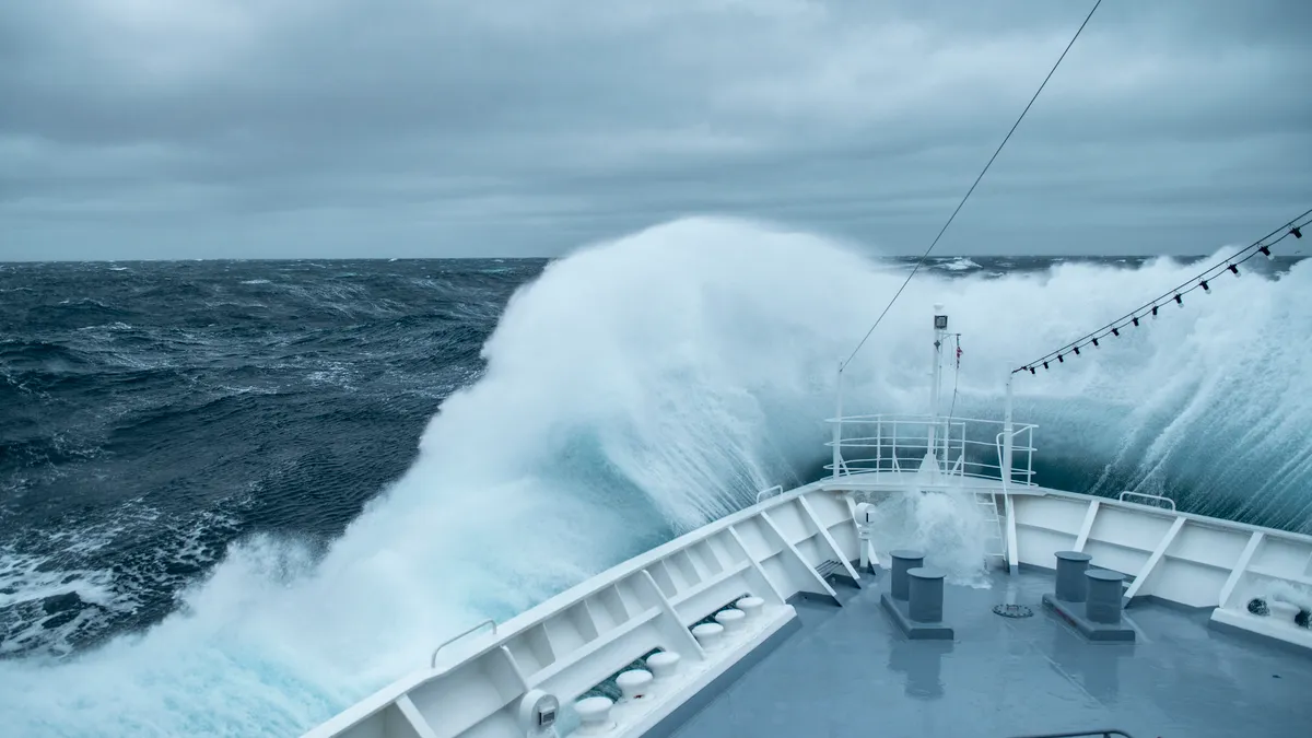 Image shows bow of boat crashing through waves.