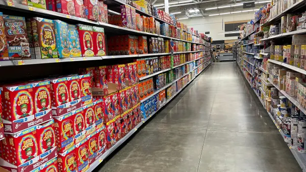 A long aisle contains various vibrant cereal boxes in an industrial commercial space. 