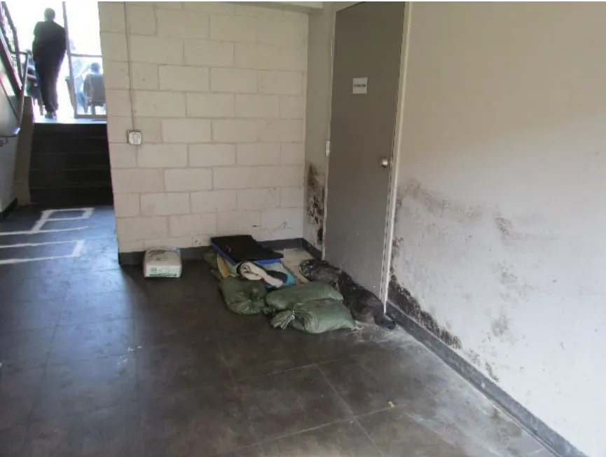 A hallway with a door blocked by sandbags. Two dark stains are visible near the door.