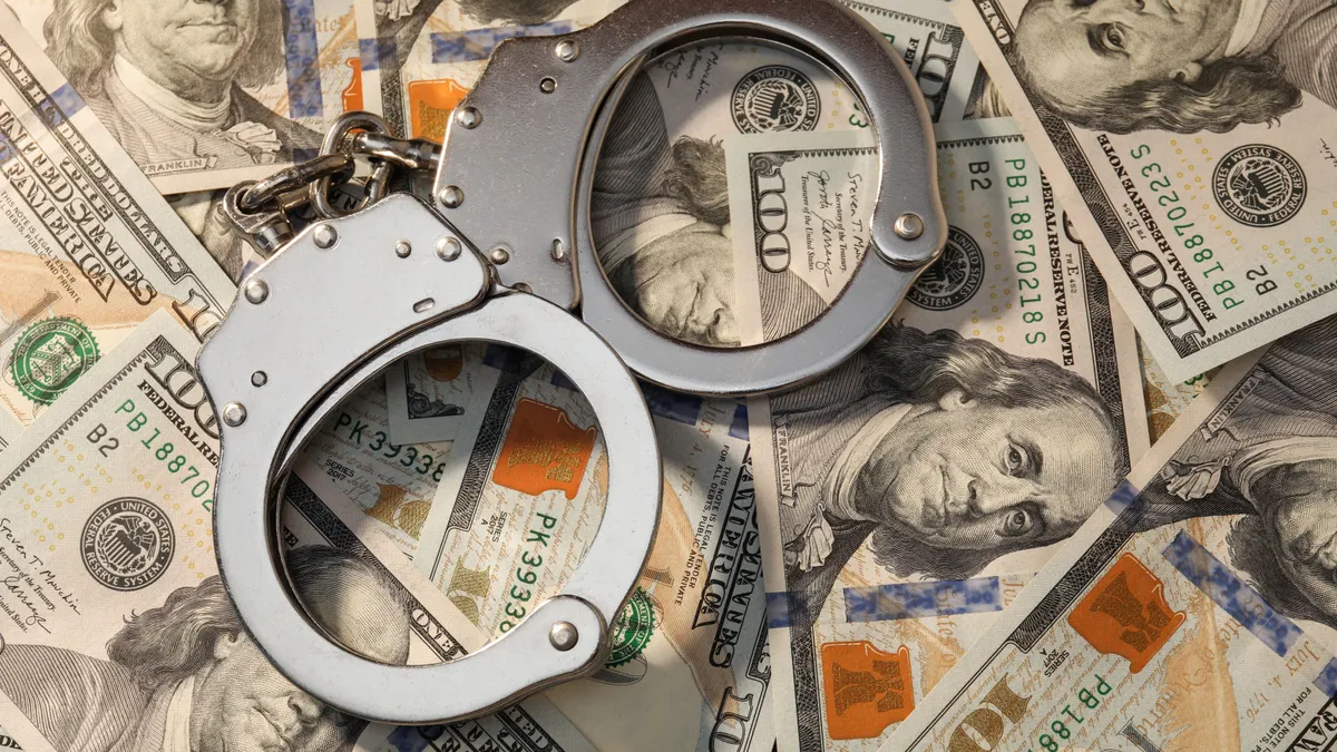 Handcuffs on pile of dollar banknotes, above view