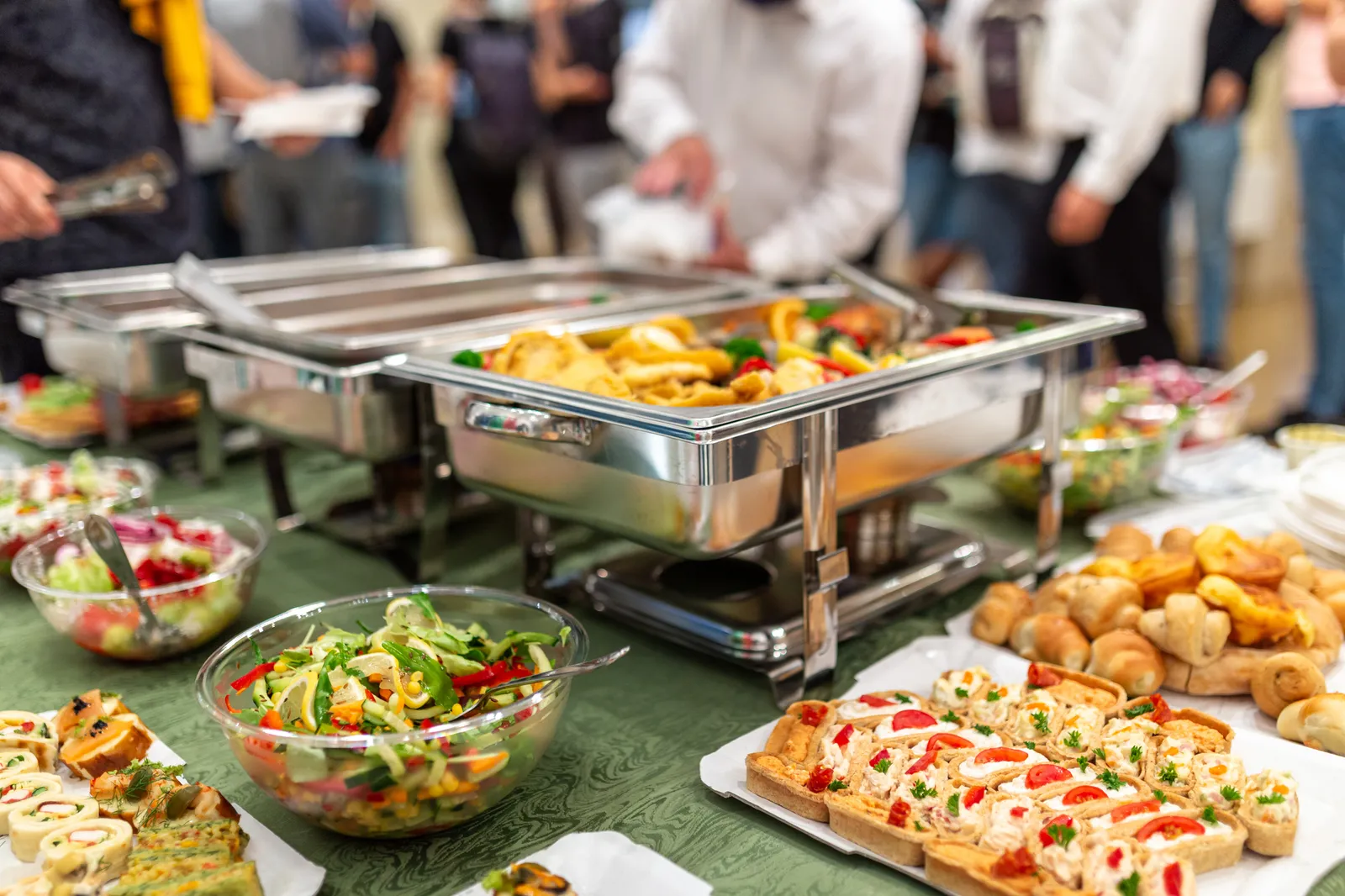 A stock image of catered food in chafing dishes.