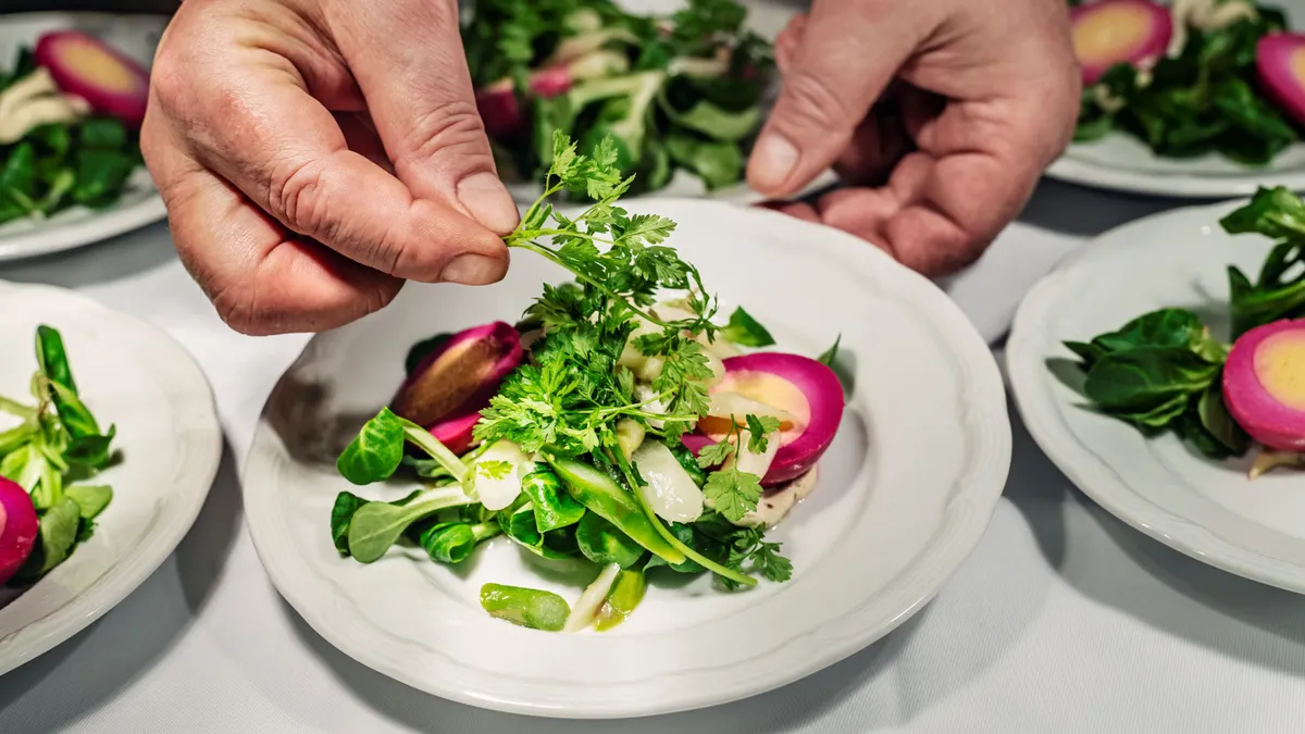 A chef prepares a seasonal Easter dish with pickeled egg dyed prupose and served with a watercress salad and olive oil dressing
