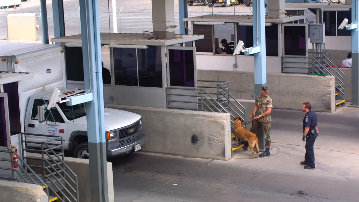 A U.S. Customs Inspector and a U.S. Marine check in vehicles at the Bridge of Americas port of entry cargo facility in El Paso, Texas.