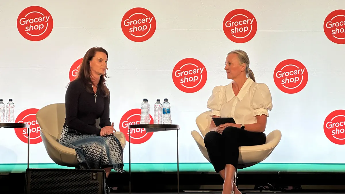 Two people sitting in chairs talking during a conference session.