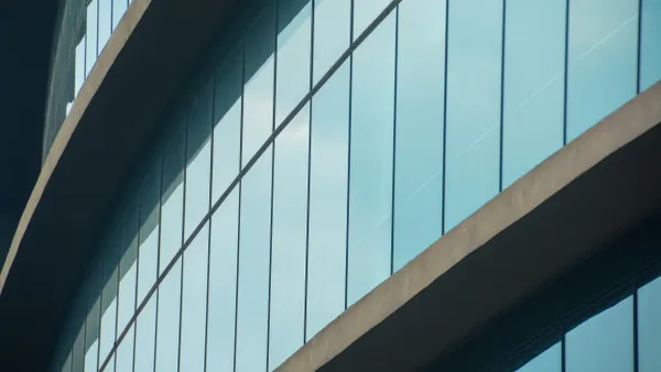 A curved wall of windows with concrete between them.