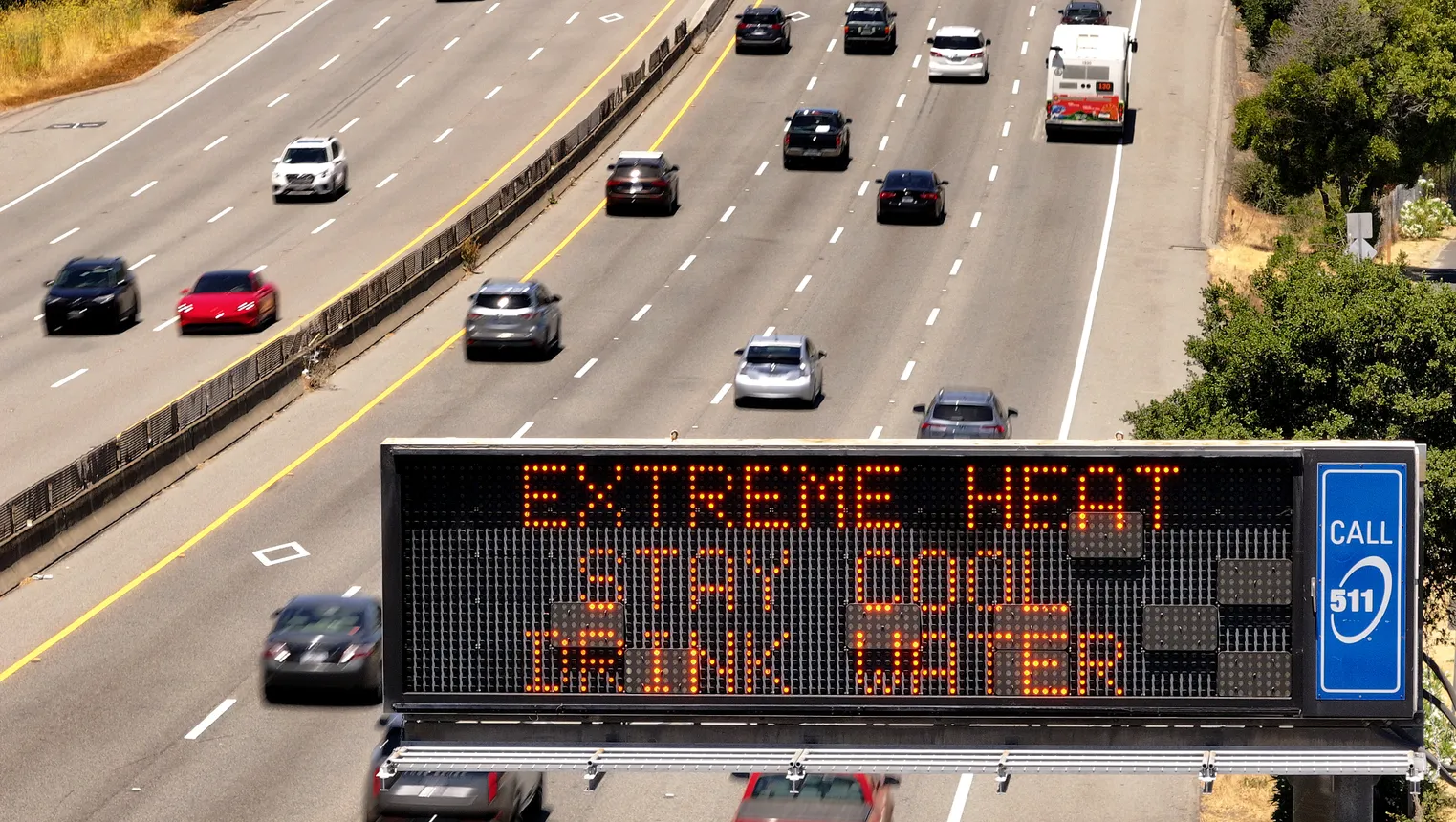 A billboard over a California highway reads "Extreme Heat Stay Cool Drink Water"