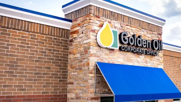 A photo of a brick building with a blue awning. A sign over the awning says "Golden Oil Corporate Office."