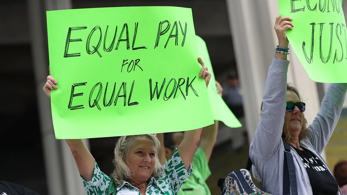 A protester holds up a sign that says "equal pay for equal work."