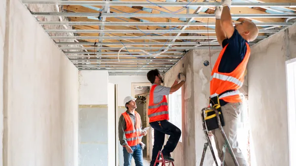 A group of people in a half-built house performing building work in the structure.