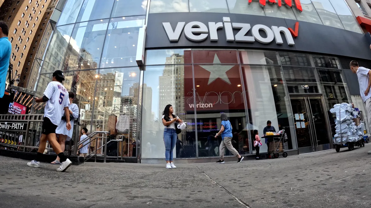 The outside of a Verizon store as people walk by.