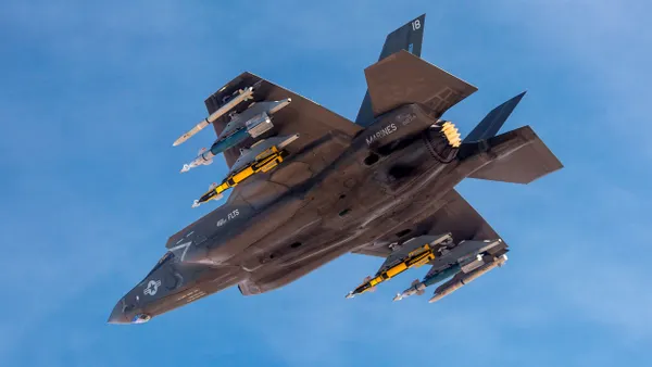 The underbelly of a camouflage gray fighter jet carrying six missiles.
