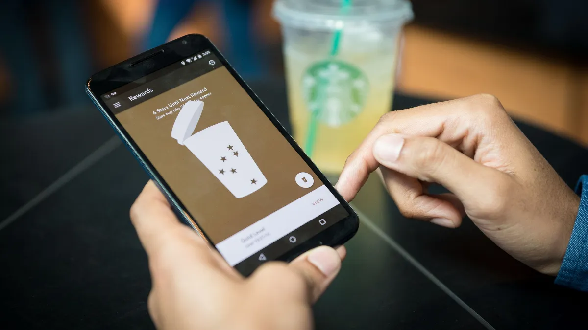 A person holds a smartphone showing the Starbucks app