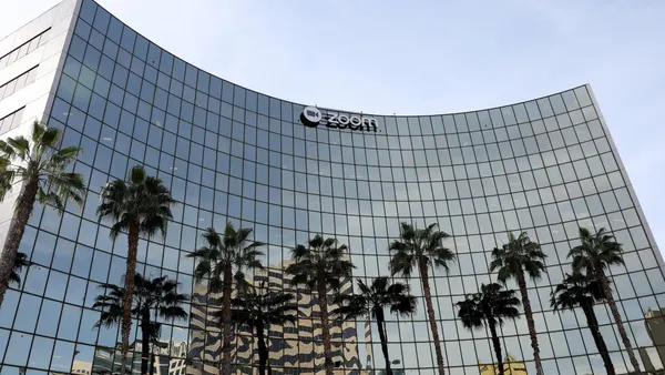 a rectangular glass office building that appears concave due to the camera angle, flanked by palm trees in the foreground.
